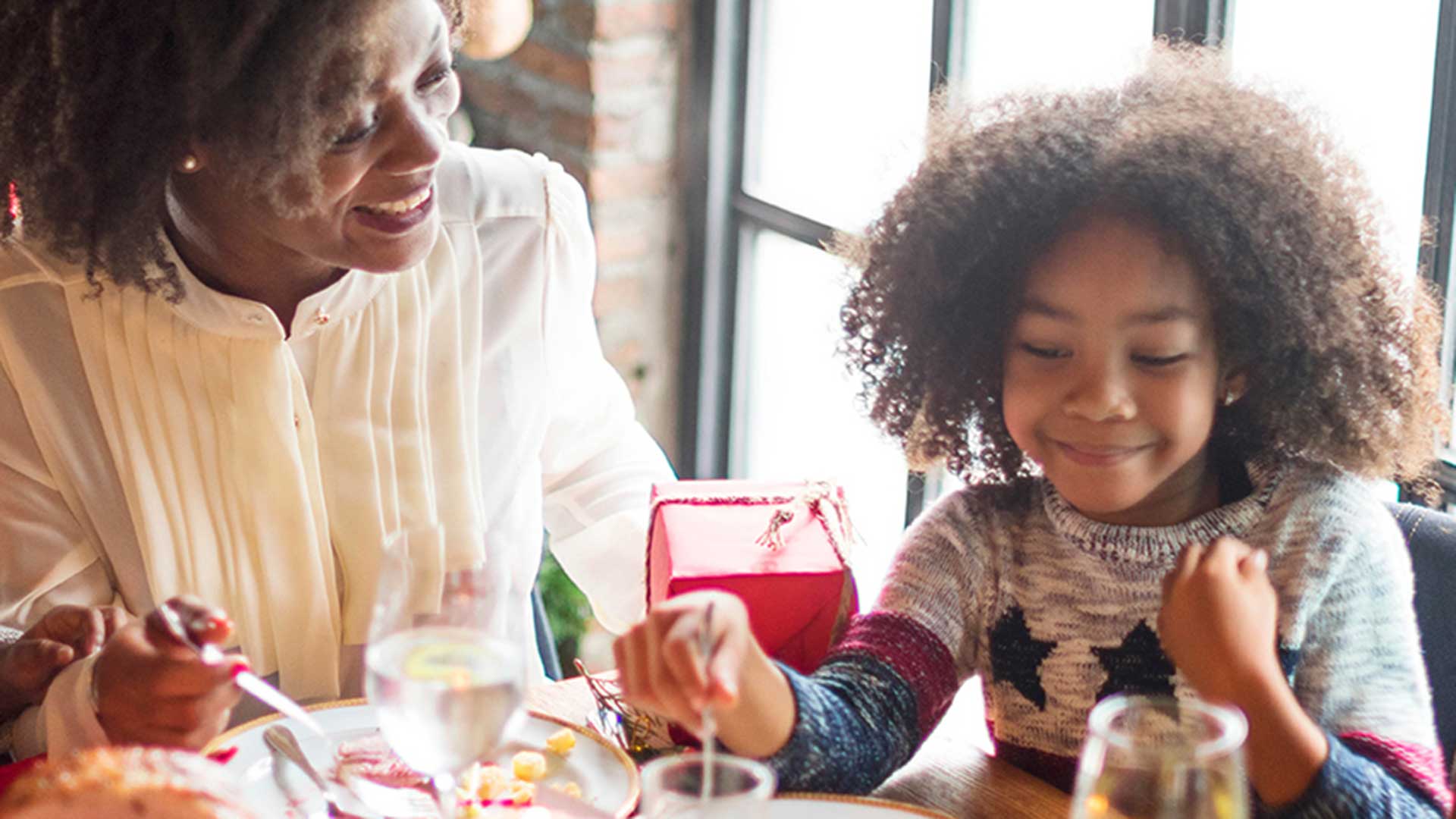 an african american woman laughs with her daughter during a holiday meal despite hearing loss